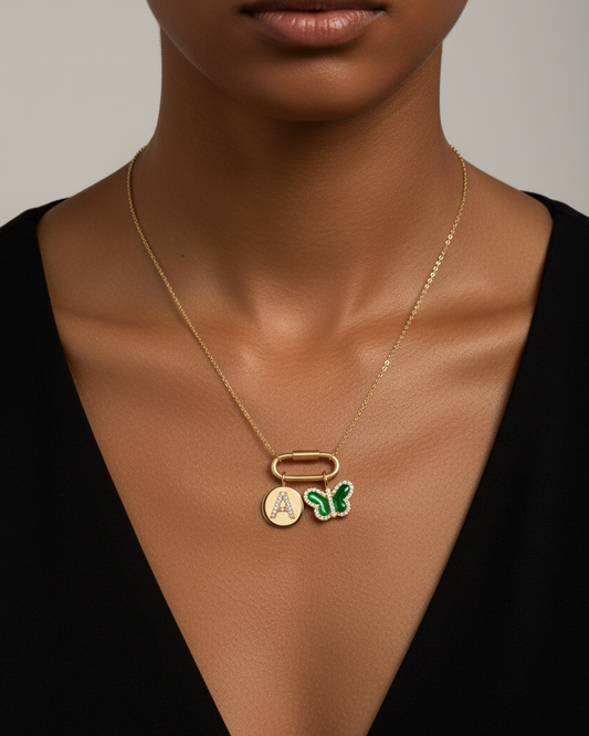 Gold necklace with a butterfly pendant and letter 'A' charm on a white background