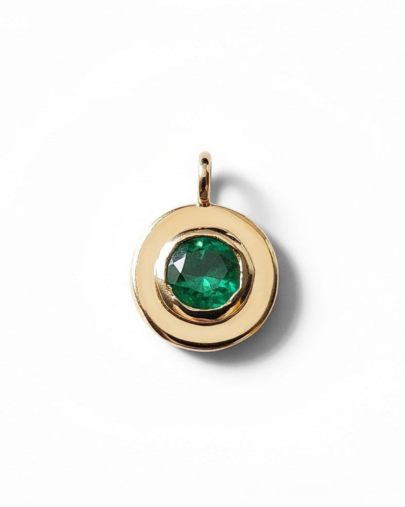 Gold pendant with a green gemstone on a white background